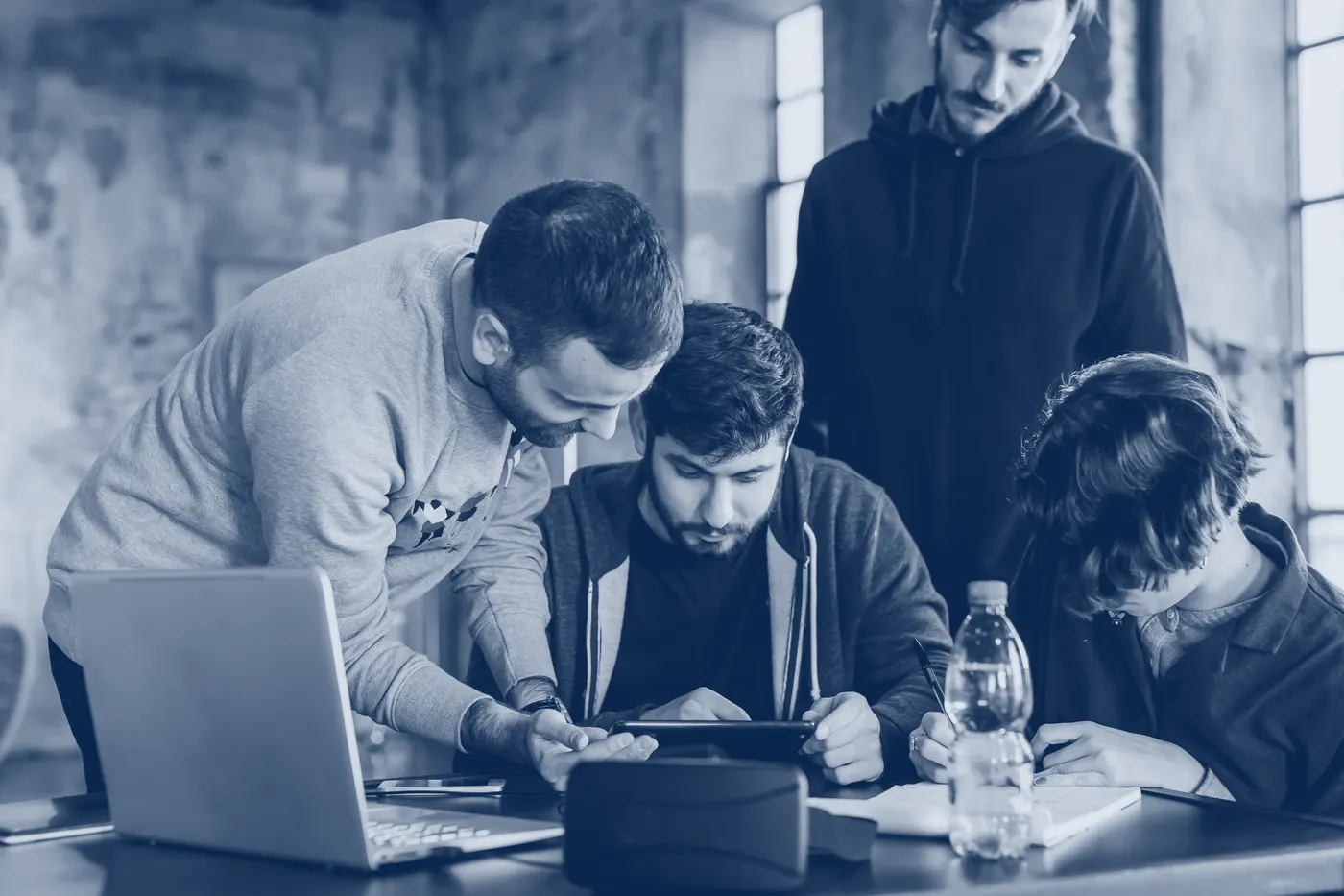 Four colleagues gather around a tablet at a table